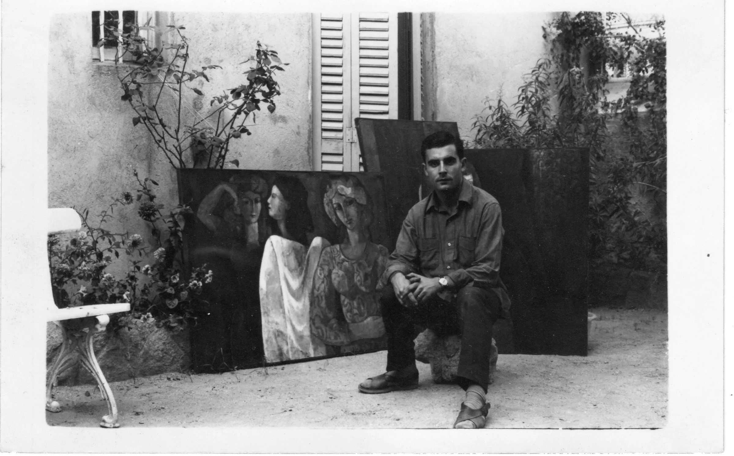 Pati emblanquinat, 1964. Assegut davant de teles del període figuratiu inicial: figures femenines recolzades a la paret. Fotografia en blanc i negre.